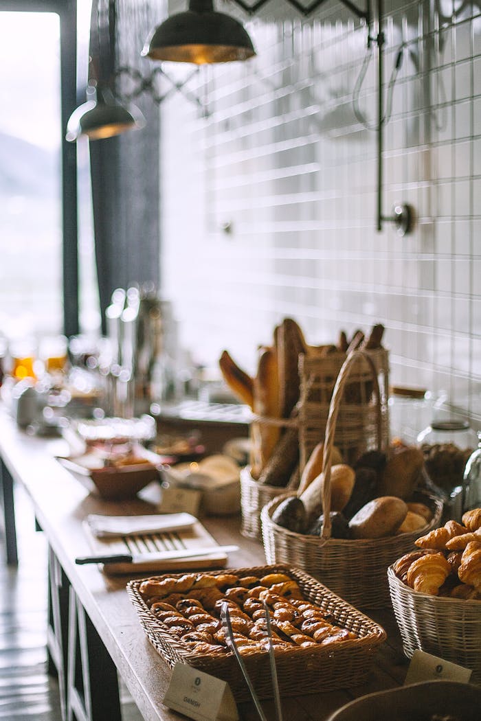 Side view of delicious fresh baked baguette and buns in wicker basket and fresh baked pies and croissant in bakery in daytime