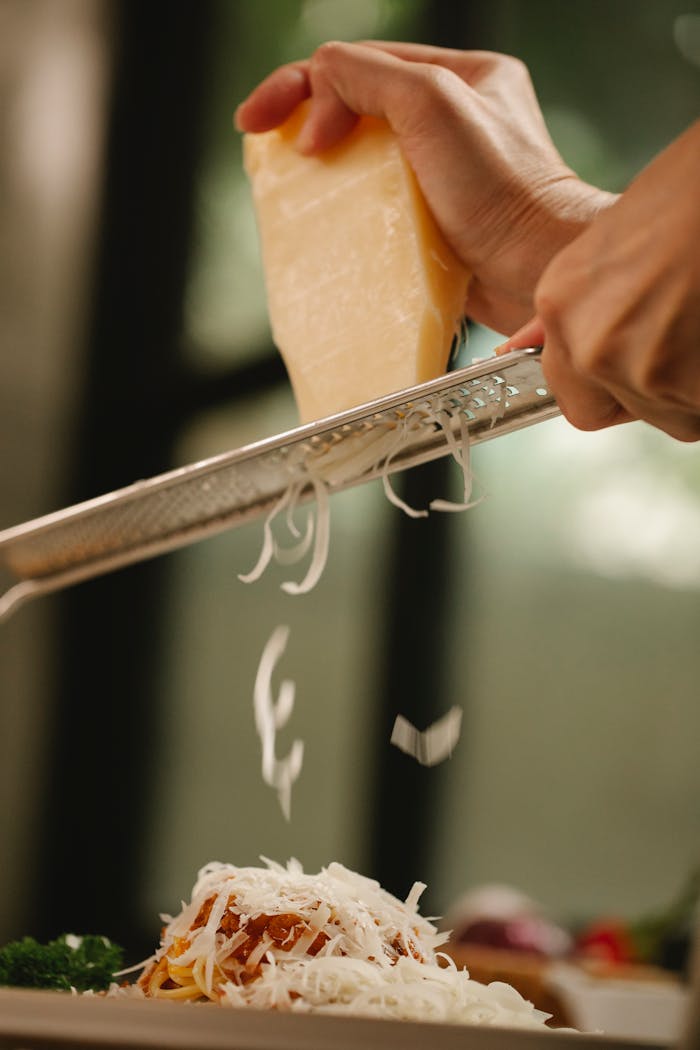 Crop unrecognizable chef grating cheese on delicious spaghetti